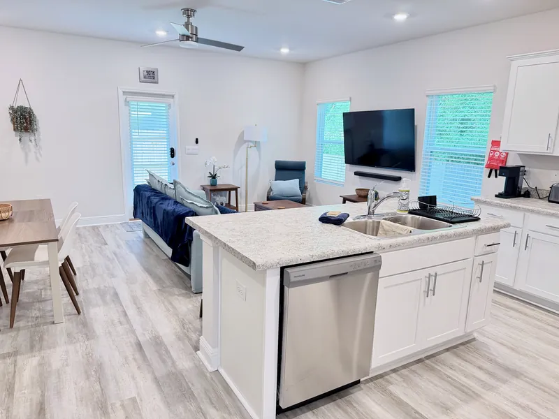 Open-concept living room and kitchen with 65-inch TV, sofa and dining table in the Pensacola townhome