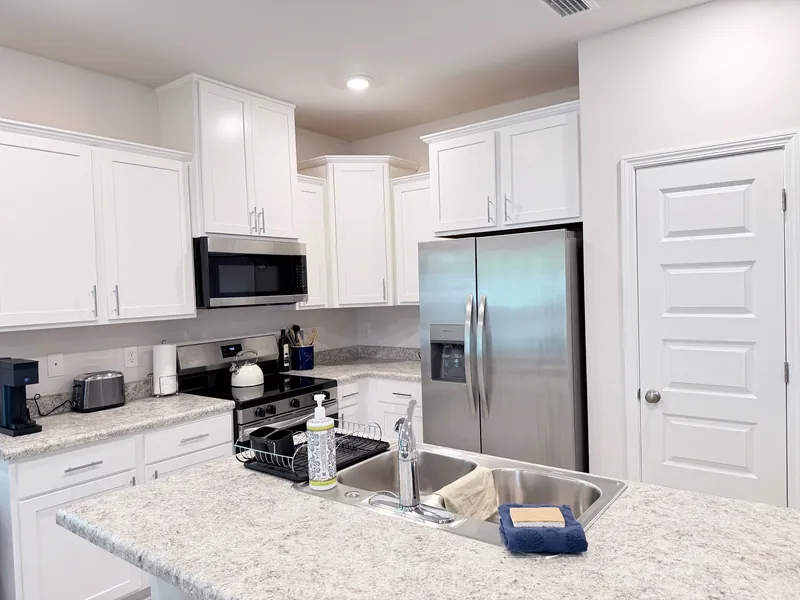 Stainless steel refrigerator, range and microwave in the fully stocked kitchen