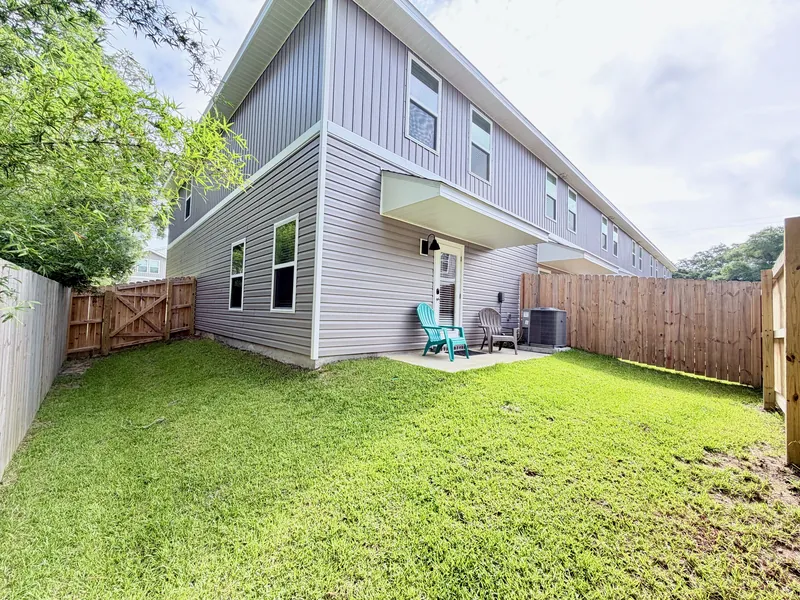 Fenced private yard with lawn behind the end-unit townhome